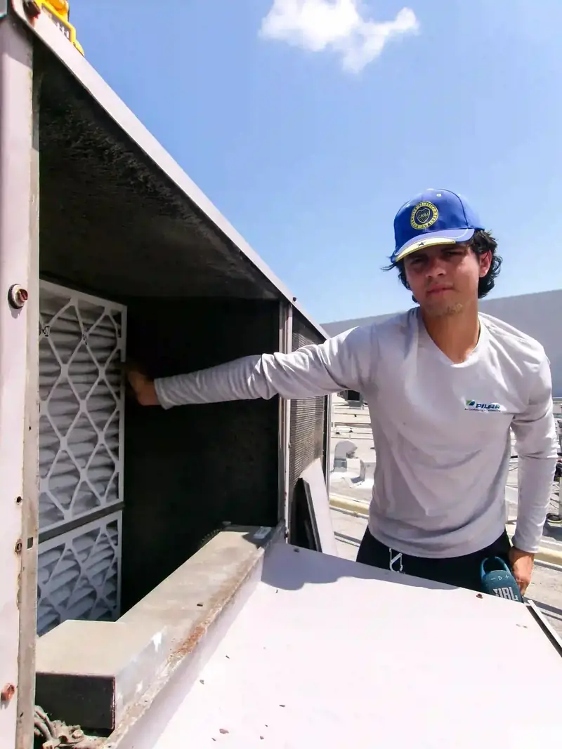 Pilar Services technician checking refrigerant pressures on an outdoor condenser