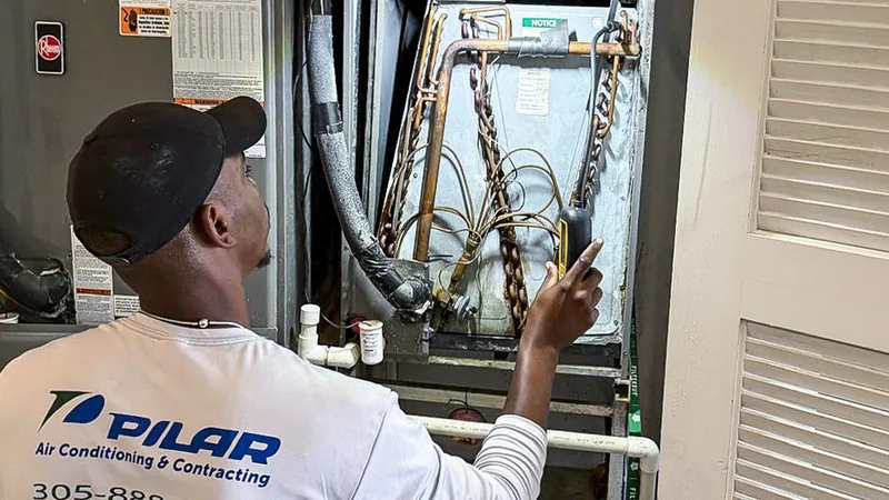 Pilar Services technician checking the coil inside a residential air handler