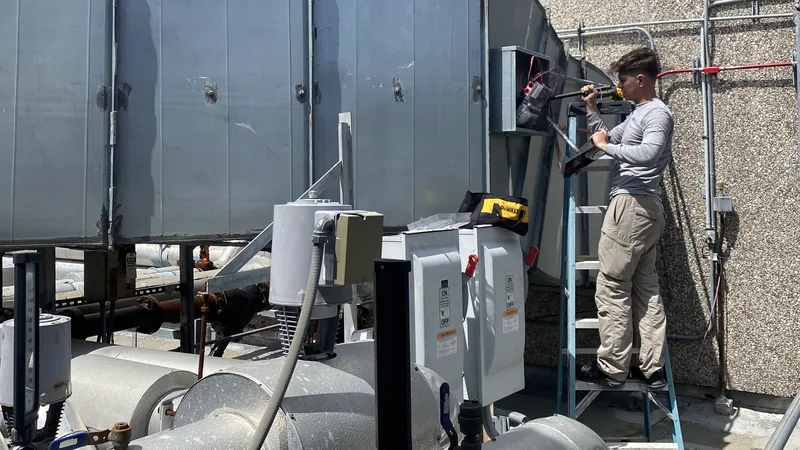 Pilar Services technician on a ladder servicing a commercial rooftop air handler
