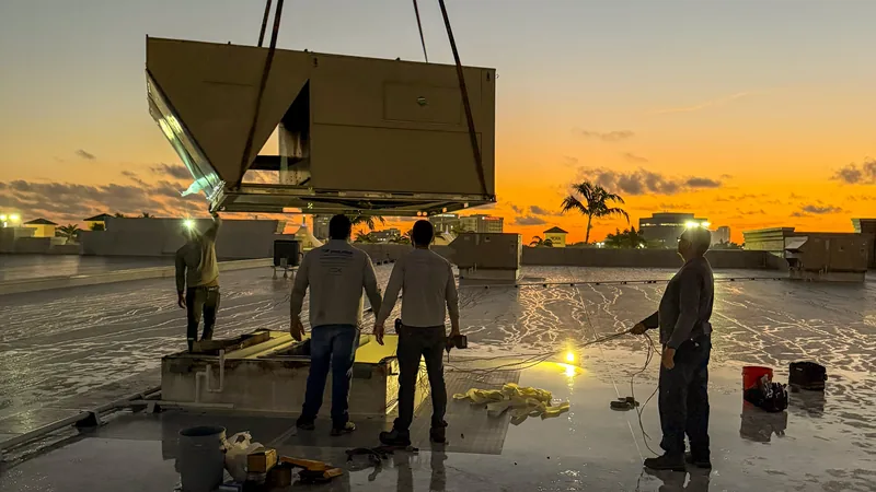 Crane lowering a new rooftop package unit into place on a Florida commercial roof at dusk