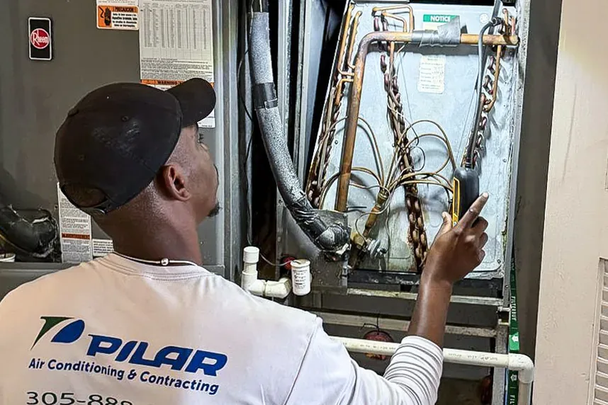 Pilar Services technician checking the coil inside a residential air handler